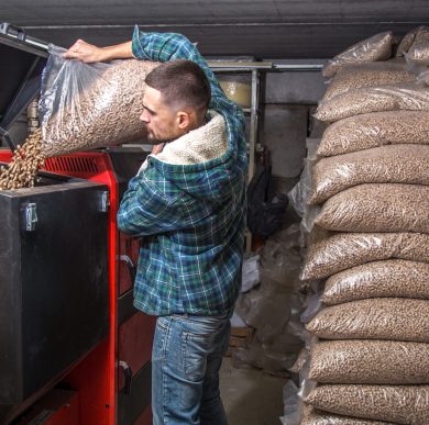 the man loads the pellets in the solid fuel boiler, working with biofuels, economical heating
