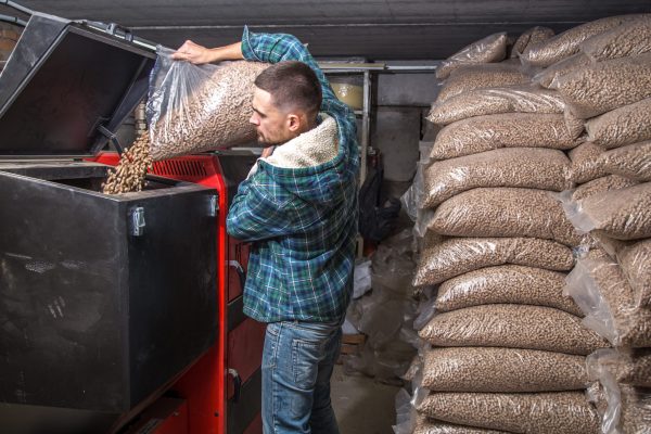 the man loads the pellets in the solid fuel boiler, working with biofuels, economical heating